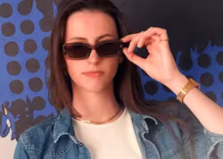 Eine Frau tr&auml;gt eine Brille der Marke Replay.