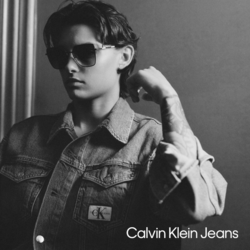 Junges Androgynes Model mit Jeanshemd und Calvin Klein Jeans Damen Sonnenbrille aus Metall. Schwarz Weiß