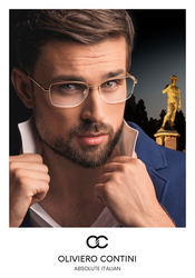 Ein eleganter junger mann mit Oliviero Contini Brille vor dunklem Hintergrund und römischer Statue.