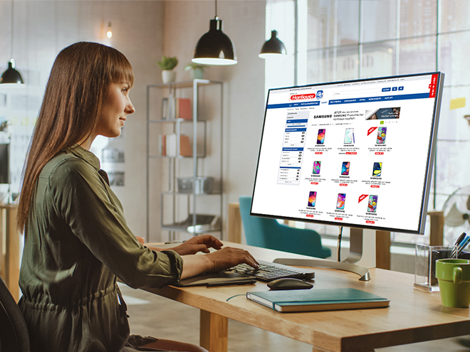 eine Frau sitzt vor einem Computer und sieht sich die Hartlauer Checkliste auf der der Hartlauer-Website an