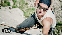 Junger Mann mit Kletterausrüstung beim Bergsteigen mit Jill Sportbrille
