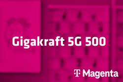 Tarif Gigakraft 5G 500 und Magenta-Logo vor unscharfem magentafarbenem Hintergrund mit Handyabteilung in Hartlauer Geschäft

