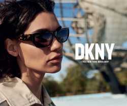 Junge dunkelhaarige Frau mit Trenchcoat im Halbprofil trägt DKNY Sonnenbrillen.
