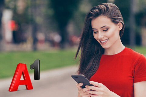  junge Frau in Park schaut lächelnd auf Smartphone neben A1 Logo