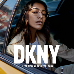 Junge dunkelhaarige Frau in gelbem New Yorker Taxi trägt DKNY Metallbrille.
