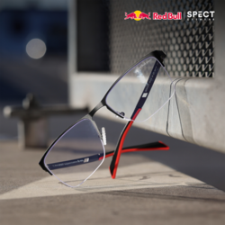 Grafik zur Bewerbung der Brillen von Red Bull Spect. Eine Brille der Marke Red Bull Spect lehnt an einem Metallgitter.