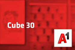 Tarif Cube 30 und A1-Logo vor unscharfem roten Hintergrund mit Handyabteilung in Hartlauer Geschäft
