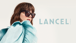 Junge Frau mit türkisem Top und Lancel Acetat Sonnenbrille vor weißem Hintergrund.