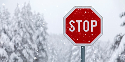 ein Stop-Zeichen vor einer verschneiten Winterlandschaft 