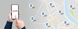 Hand tippt auf Smartphone mit Hartlauer-Logo am Screen neben Stadtplan mit eingezeichneten Hartlauer Geschäften