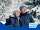 Eine Frau und ein Mann stehen in einem verschneiten Wald.