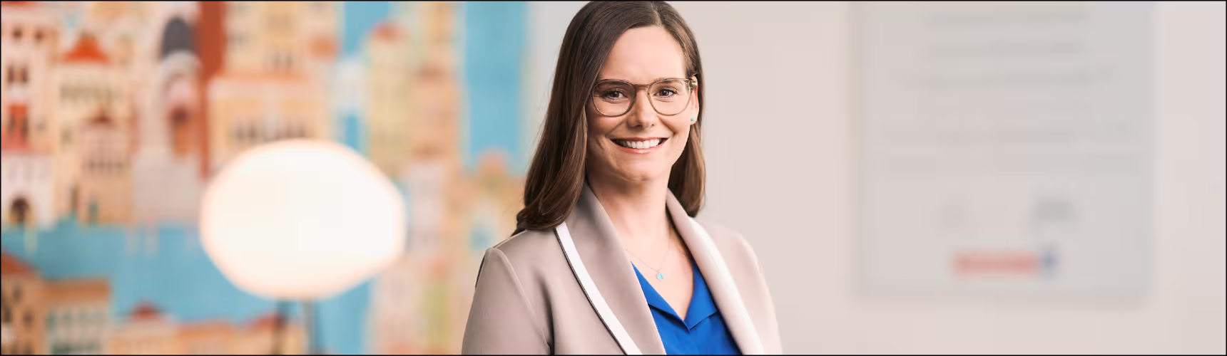 "Eine Hartlauer Mitarbeiterin steht vor einem unscharfen Hintergrund und lächelt."