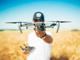 die DJI Mavic Pro Drohne in der Hand eines Mannes vor einem verschwommenen Getreidefeld im Hintergrund
