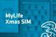 Tarif Drei MyLifeXmas SIM und Drei-Logo vor unscharfem türkisem Hintergrund mit Handyabteilung in Hartlauer Geschäft