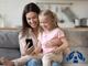 eine Frau und ihre Tochter informieren sich über den Kinderschutz von Hartlauer auf dem Smartphone