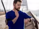 Jogger mit Smartphone am Arm auf Brücke misst am Hals seinen Puls mit Sportuhr
