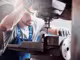 ein Handwerker spannt ein Metallstück in eine Tischbohrmaschine
