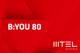 Eine Grafik mit rotem Hintergrund. In weiß steht folgender Text: "B:YOU 80." Das weiße MTEL Logo befindet sich in der rechten unteren Ecke.