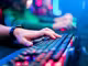 Nahaufnahme von Gaming Tastatur mit Hand im Halbdunkel
