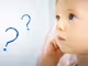 ein nach oben blickendes Baby und zwei blaue Fragezeichen
