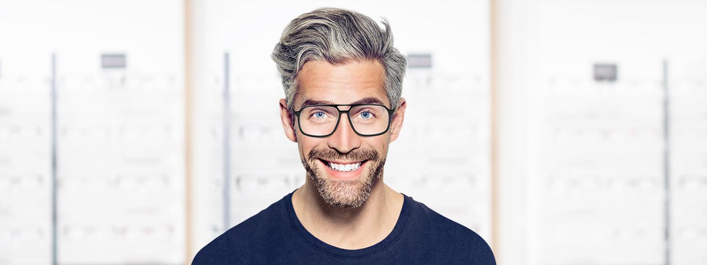 lächelnder Mann trägt Brille mit schwarzer Fassung von Hartlauer