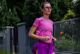Eine junge Frau mit Sportbrille joggt vor einem Garten.