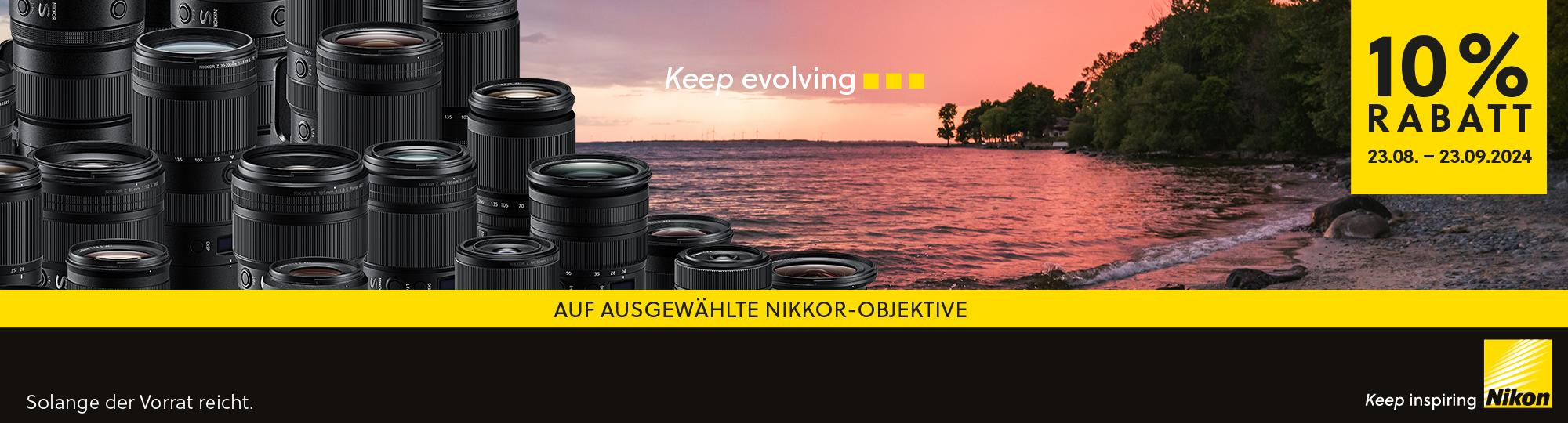 Grafik zur Bewerbung der Nikon -10% Objektivwochen. Auf der Grafik sind viele nebeneinander gereihte Objektive zu sehen. Der Hintergrund zeigt einen Kieselstrand bei Sonnenuntergang mit einigen Bäumen. Auf der Grafik steht folgender Text: "Keep evolving. 10% Rabatt 23.08. bis 23.09.2024. Auf ausgewählte Nikkor-Objektive. Solange der Vorrat reicht. Keep inspiring. Nikon."