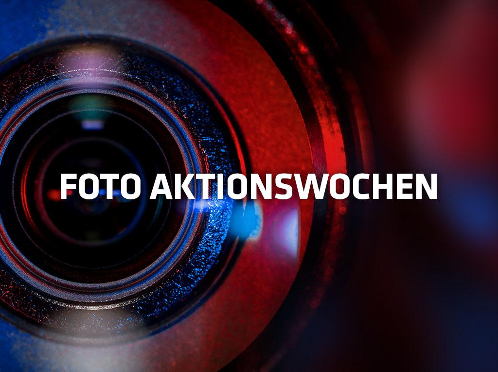 "Nahaufnahme von Kameraobjektiv in rot-blauem Licht mit Text “Fotoaktionswochen”"