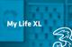 Tarif My Life XL und Drei-Logo vor unscharfem türkisem Hintergrund mit Handyabteilung in Hartlauer Geschäft
