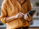 Eine Person hält ein Smartphone in der Hand und bedient es mit der anderen Hand.