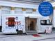 Hartlauer Gesundheitsbus für gratis Seh- und Hörtests vor einem weißen Gebäude