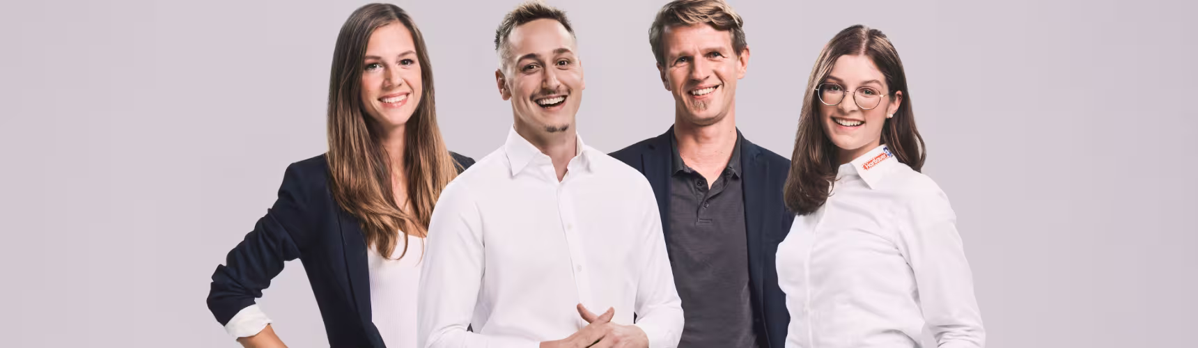 "Zwei Mitarbeiterinnen und zwei Mitarbeiter von Hartlauer stehen nebeneinander und lächeln."