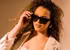 Junge Frau mit Locken, in weißem Blazer gekleidet , modelt mit Calvin Klein Sonnenbrille 