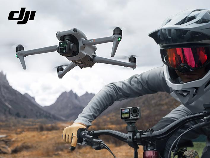 DJI Air 3 Kameradrohne beim Flug über hügeligem Gelände mit trockenem Gras und Downhill-Fahrer mit montierter Osmo Action 4 Action-Kamera