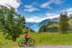 aktive ältere Frau, die mit ihrem Elektro-Mountainbike den wunderschönen Blick hinunter zum See genießt