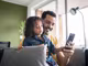 Vater und Tochter auf der Couch mit einem schwarzen Smartphone in der Hand 