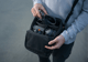 Eine Person hält eine geöffnete Umhängetasche in den Händen. Darin befindet sich die DJI Avata 2 mitsamt Zubehör (Akkus, Fernbedienung, Brille).