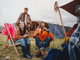 Eine Gruppe von Menschen sitzt gemeinsam auf einem Campingplatz und lacht.