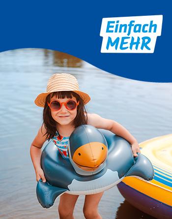 Ein Mädchen mit einem Hut und einer Sonnenbrille steht in einem See. Sie befindet sich in einen Schwimmreifen in Entenform.