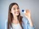 lächelnde Frau hält Kontaktlinsenbox von Hartlauer in der Hand