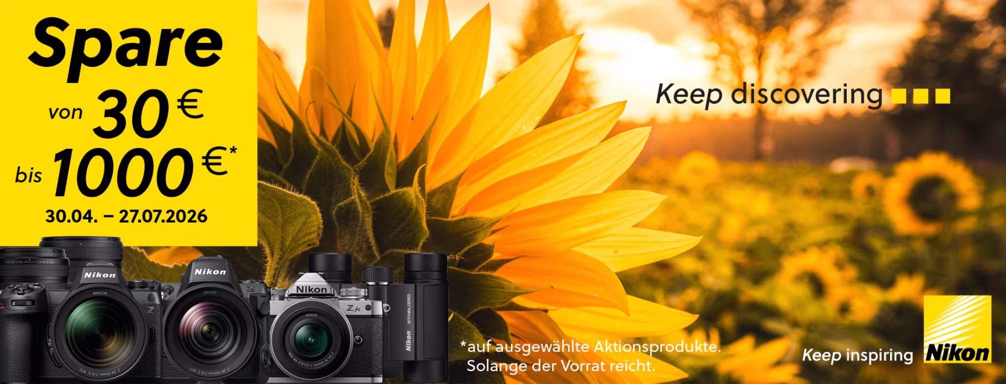 Werbebanner von Nikon: Gro&szlig;e gelbe Sonnenblume im Sonnenuntergang, links ein gelbes Feld mit dem Text &bdquo;Spare von 30 &euro; bis 1000 &euro; (30.04.&ndash;27.07.2026)&ldquo;. Unten sind mehrere Nikon-Kameras und Objektive abgebildet. Slogan &bdquo;Keep discovering&ldquo; und Nikon-Logo rechts.