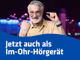 Ein Mann steht vor einer Bowlingbahn und hält ein Genesis Hörgerät in seiner Hand. Auf der Grafik steht folgender Text: "Jetzt auch als Im-Ohr-Hörgerät"