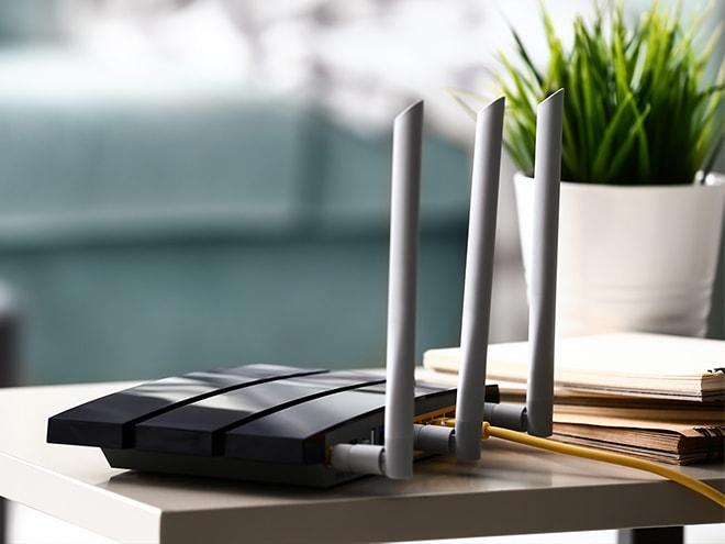 ein Hartlauer WLAN-Router für besseres Internet auf einem Tisch samt Zimmerpflanze 
