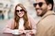 junge Frau und junger Mann mit Sonnenbrillen von Hartlauer in einem Outdoor Café